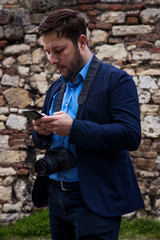 Photographer outdoors. Transfering photos from photocamera to smartphone and checking the images