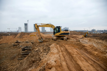 Yellow excavator during earthmoving at construction site. Backhoe digg ground for the laying sewer...
