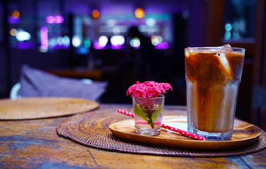 Iced coffe served with the flovers on the waved nupkin in the night club