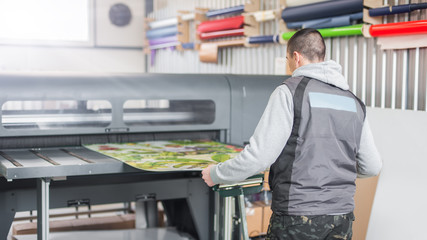 Technician operator works on large premium industrial printer plotter machine