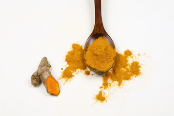 Turmeric powder in a wooden spoon and fresh turmeric roots isolated on a white background is an ingredient in turmeric foods and ingredients in skin care products. Turmeric helps the skin to be strong