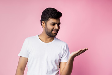 Portrait of handsome Indian guy standing on pink background