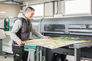 Technician operator works on large premium industrial printer plotter machine