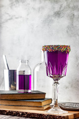 Bright violet colour cocktail with white stone texture cocktail with antique books and bar tools. Alcoholic mixed drink