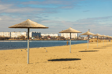 Fototapeta premium rustic scenic view of Ukrainian small city Khmelnytskyi beach umbrellas waterfront river in common day time and lonely walking person far away