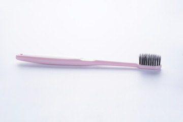 Pink toothbrush with black bristles on a white background.