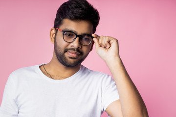 Portrait of handsome Indian guy standing on pink background