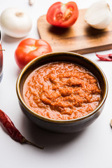 onion tomato masala or puree for indian gravy, served in a bowl with raw tamatar, pays and lehsun and red chilli, selective focus