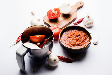 onion tomato masala or puree for indian gravy, served in a bowl with raw tamatar, pays and lehsun and red chilli, selective focus