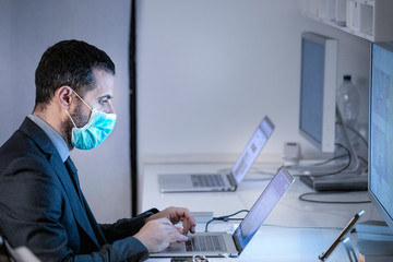 Manager ilavora nella sua postazione con la mascherina di protezione per evitare di ammalarsi