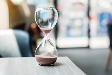 Hourglass on table office with copy space, Sand flowing through the bulb of Sandglass measuring the passing time. countdown, deadline, Life time and Retirement concept - obrazy, fototapety, plakaty
