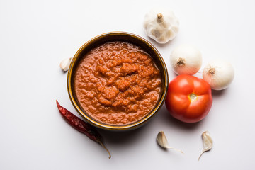 onion tomato masala or puree for indian gravy, served in a bowl with raw tamatar, pays and lehsun and red chilli, selective focus