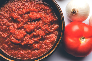 onion tomato masala or puree for indian gravy, served in a bowl with raw tamatar, pays and lehsun and red chilli, selective focus