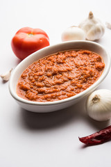 onion tomato masala or puree for indian gravy, served in a bowl with raw tamatar, pays and lehsun and red chilli, selective focus