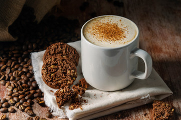 cup of cappuccino with cookies on a wooden table