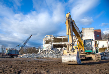 Yellow excavator with bucket at demolition of tall building. Hydraulic machine for demolish....