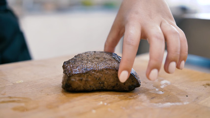 Girl chef checks finger pokes meat steak