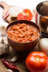 onion tomato masala or puree for indian gravy, served in a bowl with raw tamatar, pays and lehsun and red chilli, selective focus