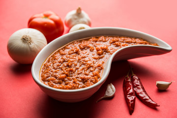 onion tomato masala or puree for indian gravy, served in a bowl with raw tamatar, pays and lehsun and red chilli, selective focus