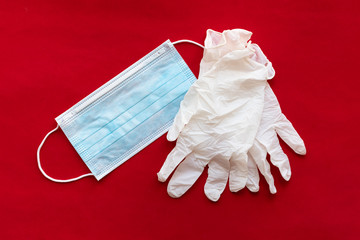 Protective face mask and surgical  gloves on red background. Virus and disease protection concept.