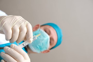 Obraz premium Doctor in a protective mask. Medicine and health concept. A doctor holds a syringe in his hands in gloves.Pandemic and epidemic coronovirus.Injection and vaccine.