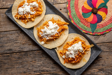 Mexican chicken tinga tacos with chipotle sauce on wooden background