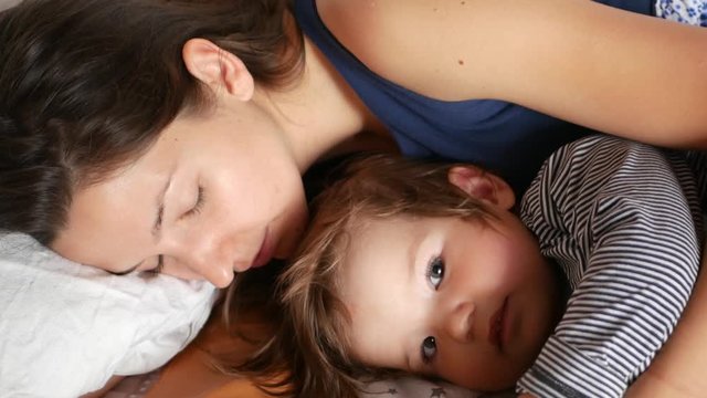 Mom with son baby woke up in the morning in bed. Concept of caring for children and parental love