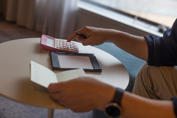 Hand of man hitting calculator while looking at bankbook