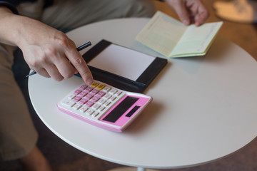 Hand of man hitting calculator while looking at bankbook