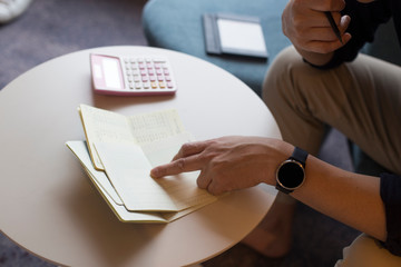 Hand of man hitting calculator while looking at bankbook