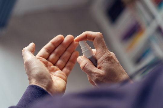 High Angle Close Up Unknown Male Person Caucasian Man Applying Spray Disinfection Alcohol Product On Hand Disinfecting Hands Against Virus Bacteria Health Prevention In Day At Home Or Work