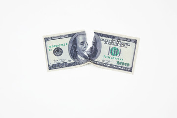 a hundred dollar bill torn in half on a white background top view
