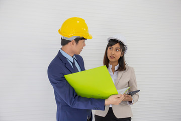Two Asian male and female foreman wearing a helmet and standing and talking at the event site
