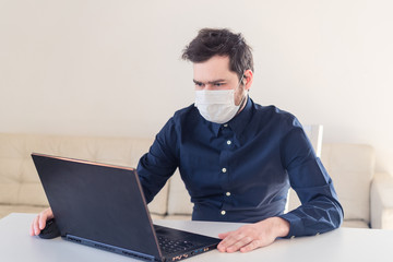 Men remote work from home behind laptop during epidemic in medical mask