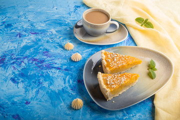 Two pieces of traditional american pumpkin pie with cup of coffee on a blue concrete background. side view, copy space.