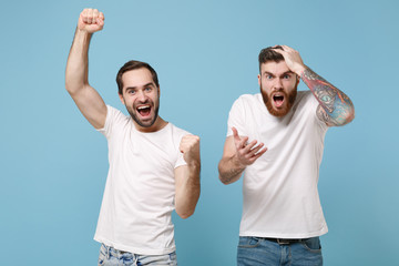 Excited irritated men guys friends in white t-shirt isolated on pastel blue background. Sport leisure concept. Mock up copy space. Cheer up support favorite team doing winner gesture put hand on head.