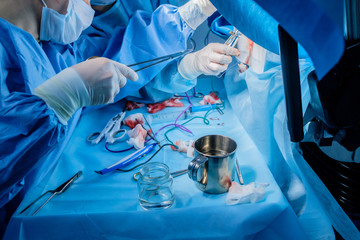 Bloodied hands of surgeons in sterile latex gloves with surgical instruments with traces of blood. The process of performing surgical coloproctological surgery.