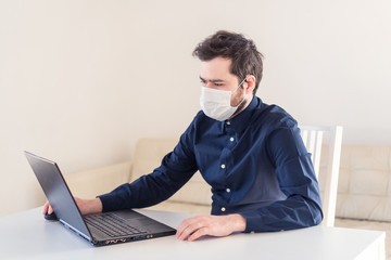 Men remote work from home behind laptop during epidemic in medical mask