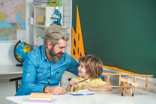 Kid And Teacher Is Learning In Class On Background Of Blackboard. Private Child Tutor. Elementary School And Education. Father Helping His Son To Make Homework.