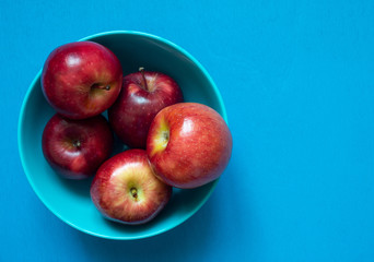 Fresh red apples on blue background, top view copy space