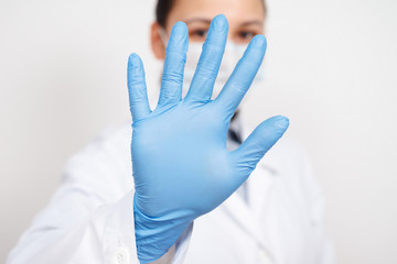 a female infectious disease doctor in a protective mask and medical gloves on a white background, held out her hand in front of her