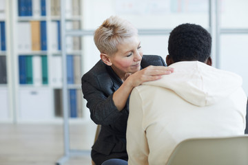 Portrait of mature female psychologist helping young patient in therapy session, copy space