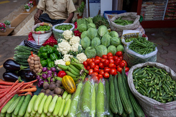 Tomatoes, cucumbers, aubergines, eggplants, cauliflowers and other fresh vegetables on sale in the middle of the street, in an indian food market in Mumbai.