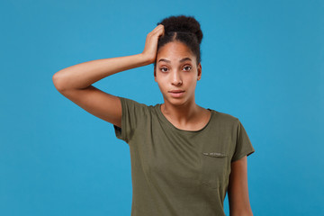 Perplexed shocked young african american woman girl in casual t-shirt posing isolated on bright blue wall background studio portrait. People lifestyle concept. Mock up copy space. Put hand on head.