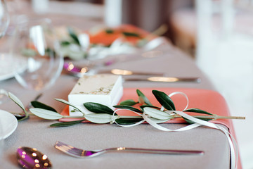 Close up of beautiful decorated table with a branch of olive tree. 