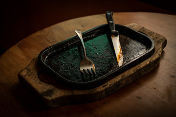 A steak eating plate with a fork and knife Consumed On an old wooden table