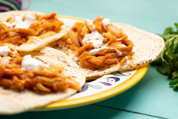 Mexican chicken tinga tacos with chipotle sauce on turquoise background