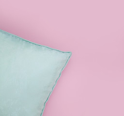 Corner of mint pillow on a blank pink background
