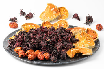 Thai herbs dried, such as roselle, quince, jujube, Chinese medicinal properties. Hypertension, heart disease on a black ceramic plate, white background