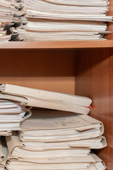 Old paper documents stacked in archive. Documents on the shelves of archive room. Office shelves in the closet full of files